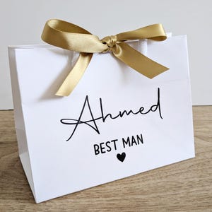 A small white gift bag for a best man. The text is black and the bag has gold ribbon.
