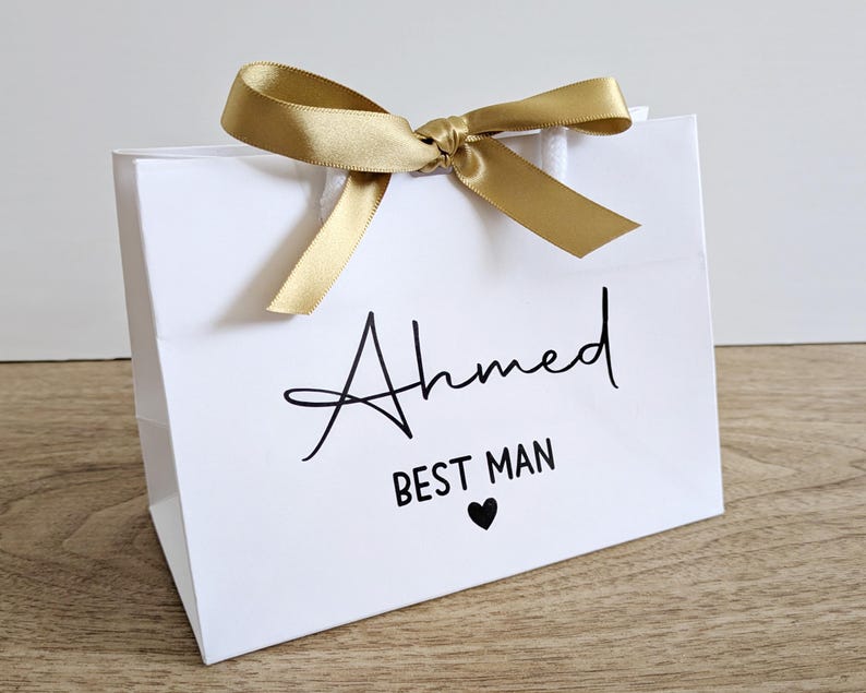 A small white gift bag for a best man. The text is black and the bag has gold ribbon.