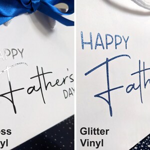 Two gift bags with the text "Happy Father's Day" printed on them. The bag on the left has the text in black gloss vinyl. The bag on the right has the text in blue glitter vinyl.