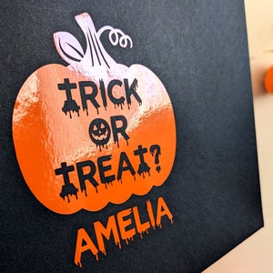 Orange pumpkin design Halloween treat bag with the text "Trick or Treat? Amelia" in spooky letters.