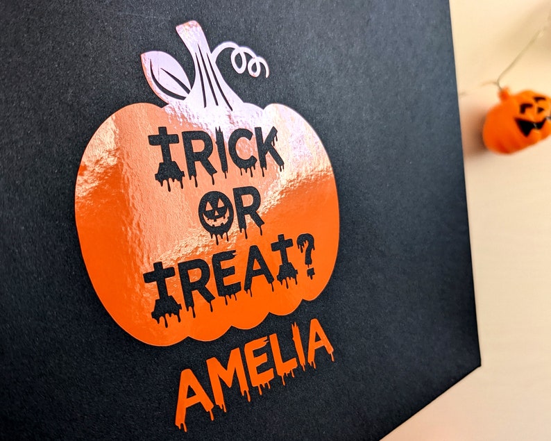 Orange pumpkin design Halloween treat bag with the text "Trick or Treat? Amelia" in spooky letters.