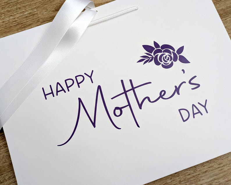 White gift bag with purple "Happy Mother's Day" text and a floral motif.