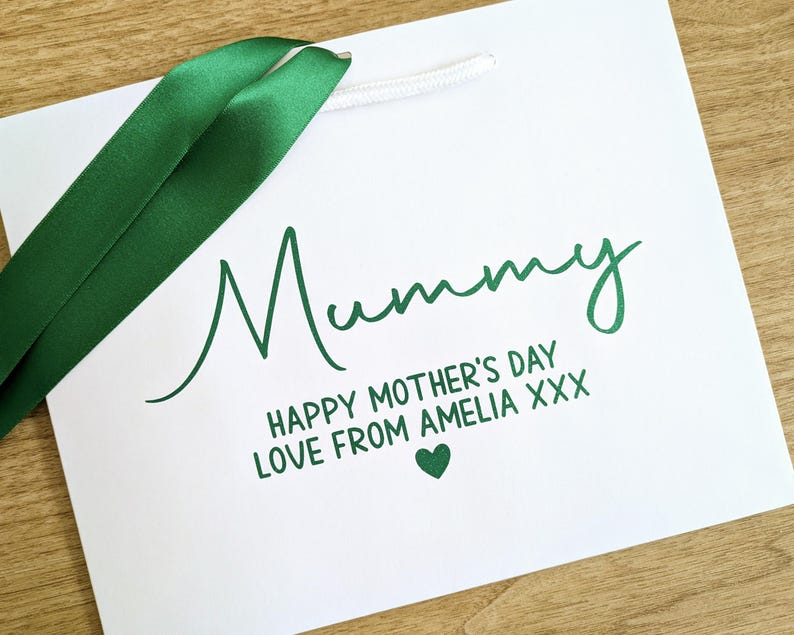 White gift bag with green ribbon and text which reads "Mummy Happy Mother's Day Love from Amelia xxx"