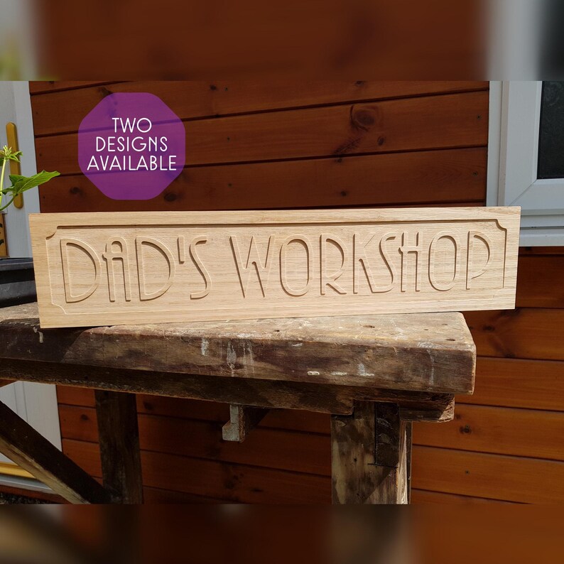 May include: A wooden sign with the text "Dad's Workshop" carved into it. The sign is on a wooden workbench. A purple text box in the upper left corner says "Two Designs Available".