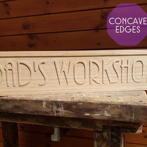 May include: A wooden sign with the text "Dad's Workshop" carved into it. The edges of the sign are concave.