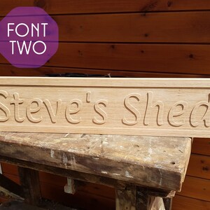 May include: A wooden sign with the text "Steve's Shed" carved into it. The sign is light brown and has a slightly distressed look.