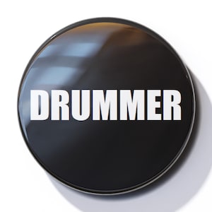 May include: A black round button with the word "DRUMMER" in white text.
