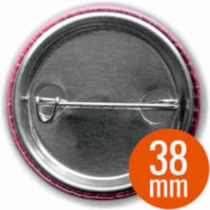 May include: The back of a silver button with a pink border. The button has a safety pin closure and a white label with the text "38 mm".