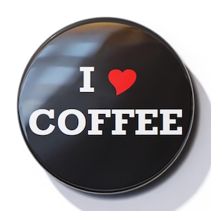 May include: A black button with a white border and the text "I love coffee" in white letters with a red heart in the middle.