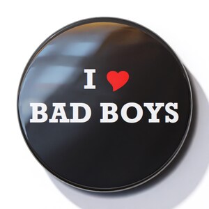 May include: A black button with a white inscription that reads "I ♥ BAD BOYS".