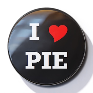 Può includere: Un bottone nero con un design bianco "I love PIE" e un cuore rosso.