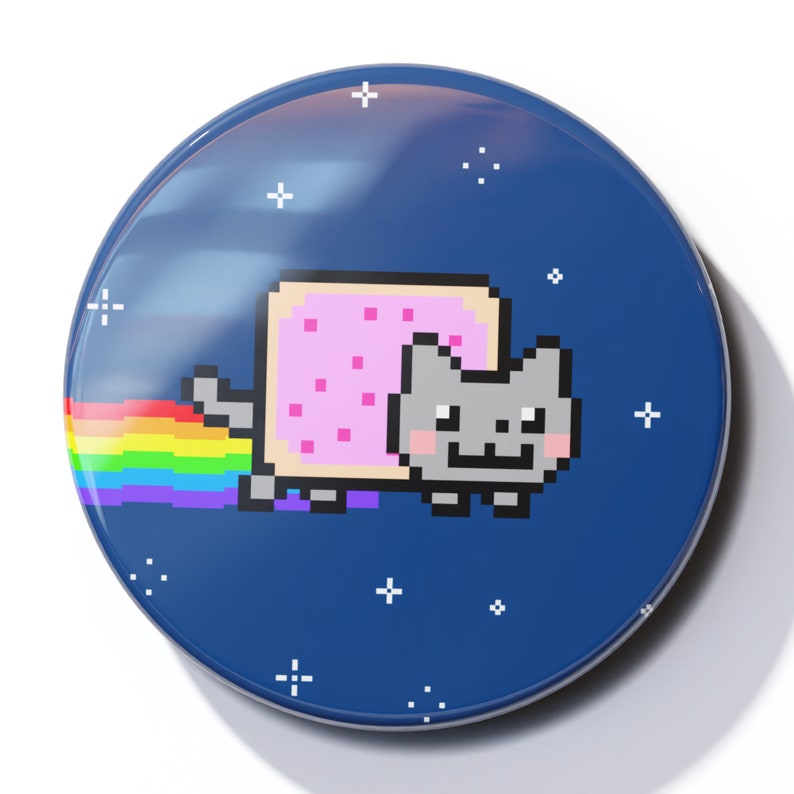 May include: A blue and white button with a pixelated image of a cat wearing a pink toast costume. The cat is flying through space with a rainbow trail behind it.