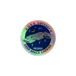 May include: A circular holographic sticker featuring a dark blue space scene with a white starship, a yellow crescent moon, and white stars. The text U.S.S. ODYSSEY DEEP SPACE CARRIER and PB3865 are printed in black around the central graphic design.