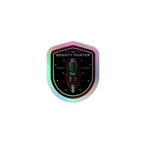 May include: A shield-shaped holographic sticker featuring a dark space background with white stars. Centered is a red and green spacecraft illustration with the text THE BOUNTY HUNTER printed in white capital letters above the ship design.