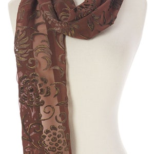 May include: A brown sheer scarf with a floral pattern in a darker brown color. The scarf is made of a soft, lightweight fabric and has a delicate, feminine feel.