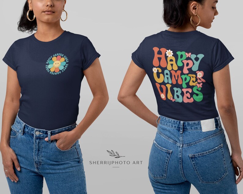May include: A navy blue t-shirt with a retro-style flower graphic on the front and the text "Happy Camper Vibes" on the back. The flower graphic is colorful and features a smiling face. The text is in a rainbow color scheme.