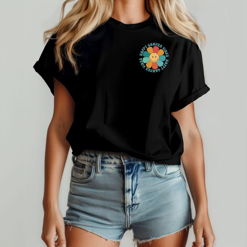 May include: Black t-shirt with a colorful flower graphic and the text "Happy Camper Vibes" around it.