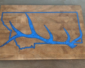 May include: A wooden cutting board with a blue epoxy resin inlay in the shape of the state of Montana and an elk antler.