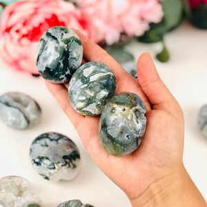 Puede incluir: Cuatro piedras de &aacute;gata verde y blanca pulidas en una mano. Las piedras son lisas y pulidas.