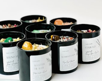 May include: Ten black candle jars with white labels. Each jar contains crystals and dried flowers. The labels have the names of the candles, such as "Abundance", "Master Healer", "Manifestation", and "Courage".