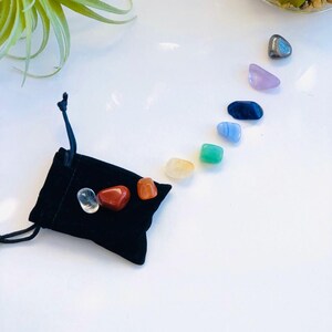 May include: A black velvet pouch with seven chakra stones, including clear quartz, red jasper, orange carnelian, yellow citrine, green aventurine, blue lapis lazuli, and purple amethyst.