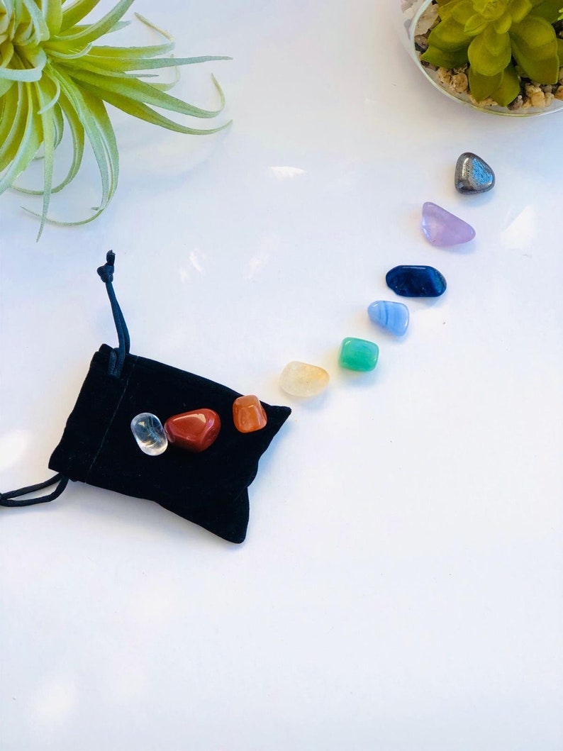 May include: A black velvet pouch with seven chakra stones, including clear quartz, red jasper, orange carnelian, yellow citrine, green aventurine, blue lapis lazuli, and purple amethyst.