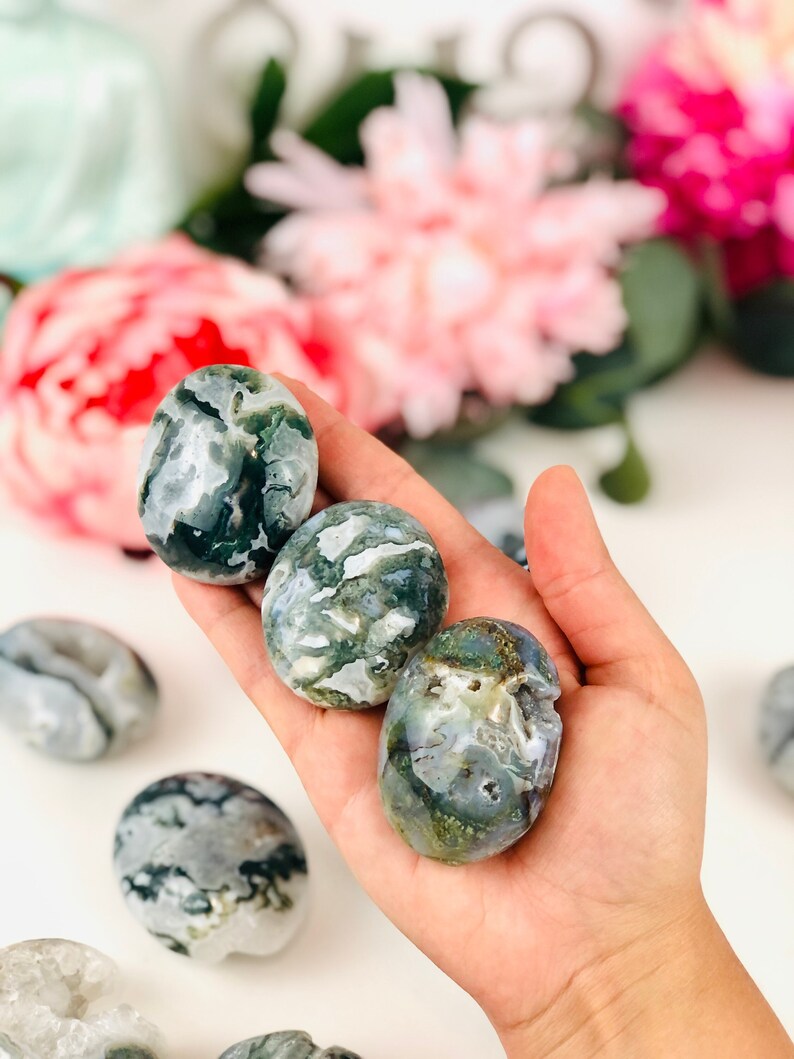 Puede incluir: Cuatro piedras de &aacute;gata verde y blanca pulidas en una mano. Las piedras son lisas y pulidas.