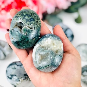 Puede incluir: Dos piedras de &aacute;gata verde y blanca con una cueva de cristal en su interior. Las piedras son lisas y pulidas y tienen un aspecto natural y org&aacute;nico.
