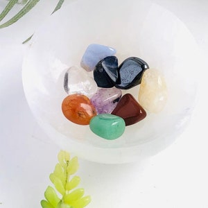 May include: A white bowl filled with a variety of small, colorful crystals, including clear, red, orange, yellow, green, blue, purple, and black.