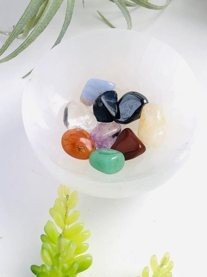 May include: A white bowl filled with a variety of small, colorful crystals, including clear, red, orange, yellow, green, blue, purple, and black.