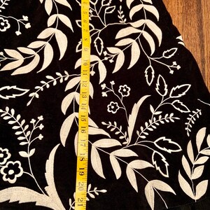 May include: Black skirt with a white floral embroidery design. The skirt has a tulle ruffle at the hem and measures approximately 23 inches in length.