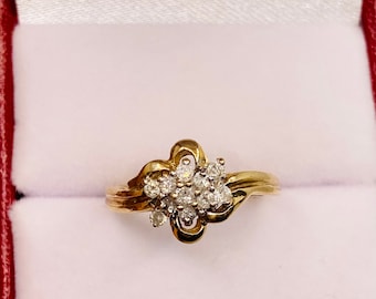 May include: A gold ring with a cluster of small diamonds set in a swirl design.