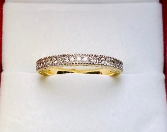 Puede incluir: Un anillo de banda de oro con una fila de pequeños diamantes transparentes.