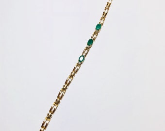 May include: A gold chain bracelet with three oval-shaped green gemstones.