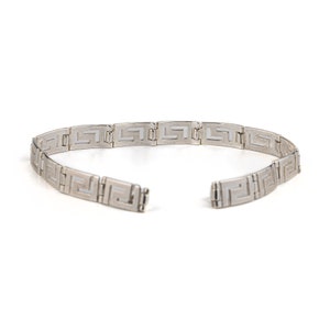 May include: A silver chain necklace with a Greek key pattern. The chain is made of interlocking links and is open at the back.