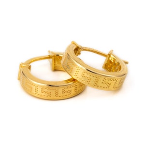 May include: A pair of gold hoop earrings with a geometric pattern.