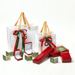May include: Two white gift bags with red and green ribbon bows. The bags are decorated with the text "50 Years" and "Show Your Love". There are several red and green gift boxes with gold trim and a small green and gold gift tag.