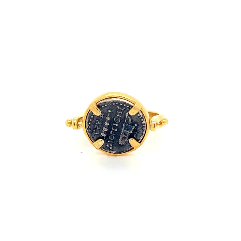 May include: A gold ring with a round, silver coin set in the center. The coin features an inscription in Greek, "ANTONINVS", and a depiction of a Roman emperor.