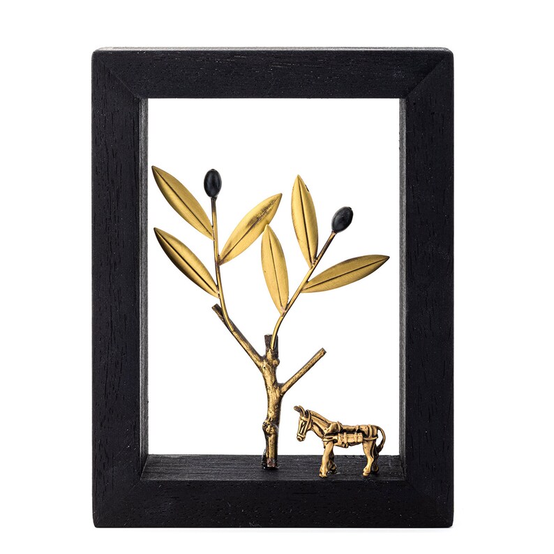 May include: A black framed wall decor with a gold metal olive branch and a donkey figurine. The olive branch has black olives and gold leaves.