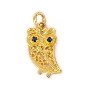 Può includere: Un ciondolo a forma di gufo in oro con occhi di zaffiro blu. Il gufo è dettagliato con un design a filigrana.