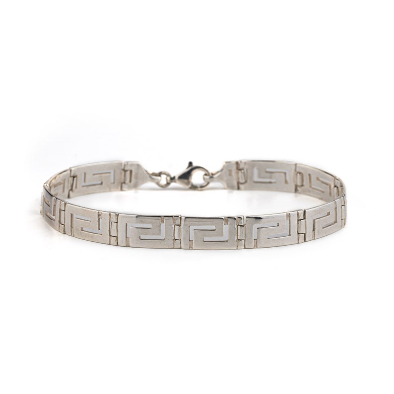 May include: A silver bracelet with a Greek key pattern.