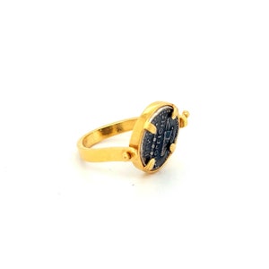 May include: A gold ring with a spinning antique coin set in the center. The coin is silver and features an inscription in Latin.