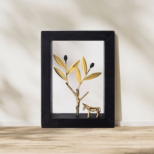 May include: A black framed shadow box with a gold metal olive branch and a gold metal donkey figurine inside.