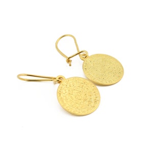 Op de afbeelding: Een paar gouden oorbellen met een rond ontwerp met ingewikkelde details. De oorbellen zijn gemaakt van metaal en hebben een hangende stijl.