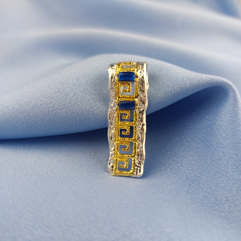 Peut inclure: Un pendentif en argent et or avec un motif de cl&eacute; grecque bleu et or.