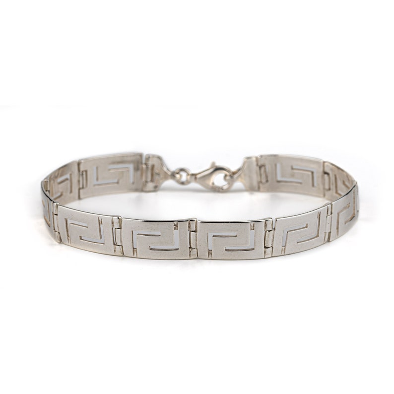 May include: A silver bracelet with a Greek key pattern.