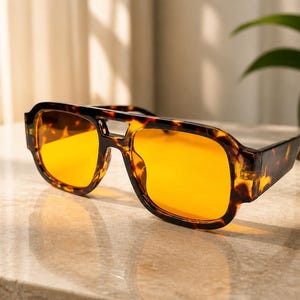 May include: Sunglasses with a thick, brown and black tortoiseshell pattern frame and a double bridge design. The lenses are a vibrant, solid orange color, providing a high-contrast look against the dark, mottled frame of the eyewear.