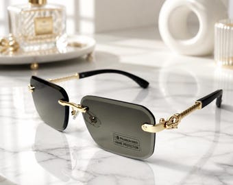May include: Rimless sunglasses featuring rectangular dark gray lenses with a sticker reading Photochromic UV400 PROTECTION. The frames have gold-tone metal temples with a twisted texture and black temple tips, connected by a gold-tone bridge.