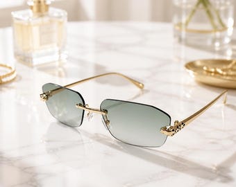 May include: Rimless sunglasses featuring rectangular gradient green lenses and thin gold-tone metal temples. The hinges are adorned with a detailed gold-tone panther head motif with black enamel spots, connecting the lenses to the slender arms.