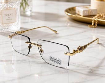 May include: Rimless rectangular glasses with gold-tone metal temples featuring a sculpted panther head design at the hinges. The clear lenses include a small sticker that reads Photochromic UV400 PROTECTION. The frame has thin gold-tone arms.